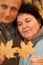 Serious middleaged man and woman hold maple leaves