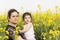 Serious mother embraced her little girl at canola field-family having fun together on canola farm
