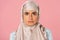 Serious muslim girl in hijab, isolated on pink