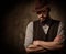 Serious old-fashioned man with hat posing on dark background.