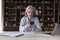 Serious older business woman holding smartphone sit at workplace desk