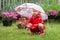 Serious pensive pretty little girl in red raincoat with umbrella