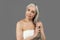 Serious retired caucasian lady in towel after shower touch gray hair, isolated on gray background, studio, free space