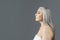 Serious retired european lady with gray hair look at copy space, isolated on gray background, studio, profile
