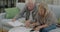 Serious retired people couple counting household bills payments using smartphone calculator at home