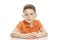 A serious school-age boy in a bright orange polo t-shirt is sitting at the table. Close-up. Isolirvoan on a white background