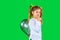 Serious school girl hides a ultimate gray balloon behind her back. Green background and side space