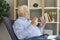 Serious senior man taking prescribed medication sitting in an armchair in the living-room