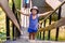 Serious seven-year-old boy in a t-shirt and hat climbs up the wooden stairs