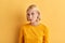 Serious skeptic woman in fashion yellow sweater posing to the camera
