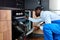 Serious Skilled African Handyman in Blue Overalls Uniform Is Going To Repair Dishwasher