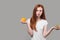 Serious slim girl in white T-shirt holding an orange and apple