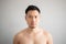 Serious and stress face of Asian man in topless portrait isolated on gray background