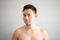 Serious and stress face of Asian man in topless portrait isolated on gray background