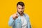 Serious strict sad adult european man with beard shows finger to camera isolated on yellow background