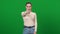 Serious strict woman pointing at camera standing on green screen. Portrait of demanding Caucasian lady posing at