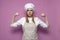 Serious strong girl cook in apron shows strength on a pink background, woman housewife in kitchen clothes