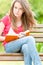 Serious student girl sitting on bench with book