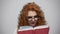 Serious student holding book in studio. Portrait of girl turning pages of book