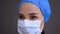 Serious surgeon or nurse in protective mask looks forward side view. Female healthcare professional wearing surgical cap
