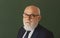 Serious teacher. Closeup portrait of senior academic professor near empty blackboard. Knowledge and traditional