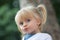 Serious thinking or sad young baby caucasian blonde real people girl with ponytail close portrait outdoor