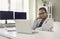 Serious thoughtful businesswoman sitting at office desk and looking at laptop screen