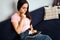 Serious and thoughtful young woman look on colorful pallete in hand. She sit on sofa in room alone. Model has tablet on