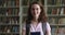 Serious university student girl with backpack posing in college library