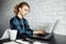 Serious woman freelancer sitting at table with laptop.