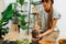 Serious woman in living room, replanting house plant from pot to pot. Cropped