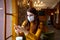 Serious woman with protective face mask looking at smart phone checking news in cafe