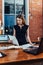 Serious woman reading papers studying resumes standing at work desk in stylish office