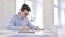 Serious Working Young Man Writing on Paper in Modern Office