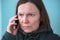Serious worried woman talking on mobile phone on street