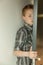 Serious young boy peering around a door