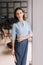 Serious young business woman holding file folder while standing near window in modern office room.