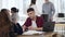 Serious young businessman listening to female colleague talking, sitting at office table in loft trendy coworking.