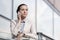 Serious young businesswoman using cell phone at office railing