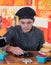 Serious young cheff preparing a gourmet Swiss fondue dinner on wooden table in kitchen background