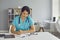 Serious young doctor sitting at desk and completing information in patient medical history