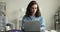 Serious young freelancer girl typing on laptop at table