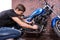 Serious Young Man Fixing his Blue Motorbike