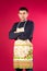 Serious young man in a kitchen apron on a pink background. The concept of gender stereotypes