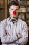 Serious young man with red clown nose