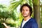 Serious young man standing by tree outside