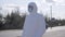 Serious young man in white protective safety suit standing on suburban road. Caucasian virologist in face mask and
