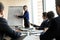 Serious young skilled female speaker pointing at charts on whiteboard.