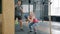Serious young sportswoman exercising in gym with personal instructor throwing ball