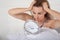 Serious young woman in bed looking at herself in a small portable hand mirror